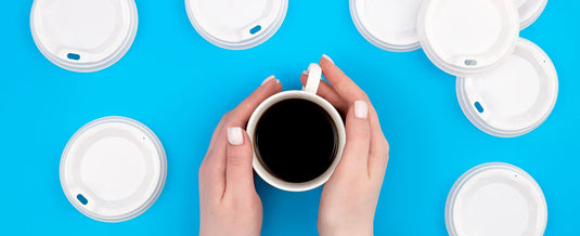 Person holding a cup of coffee surrounded by plastic cup lids